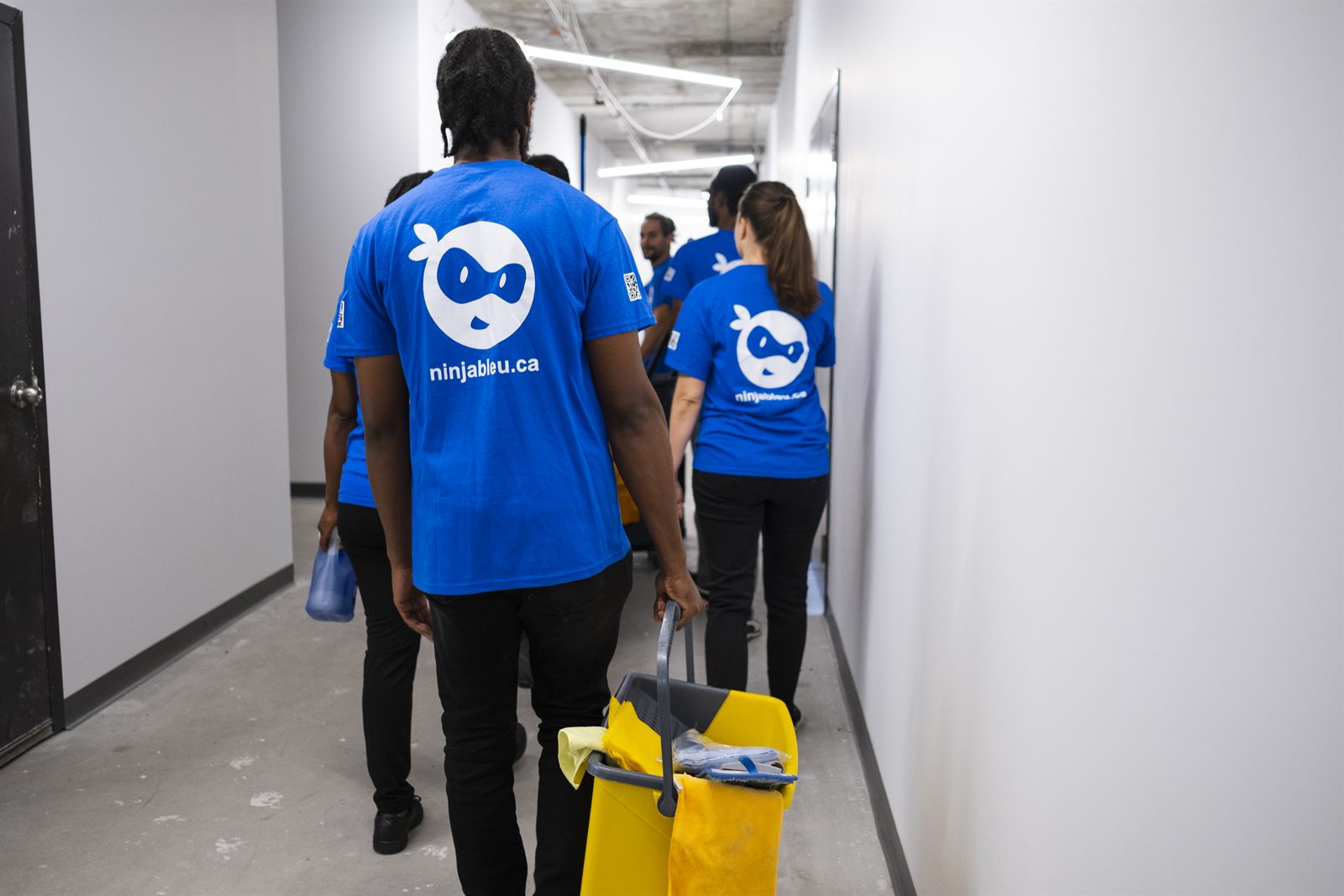 Une équipe s'éloigne dans un corridor, de dos.